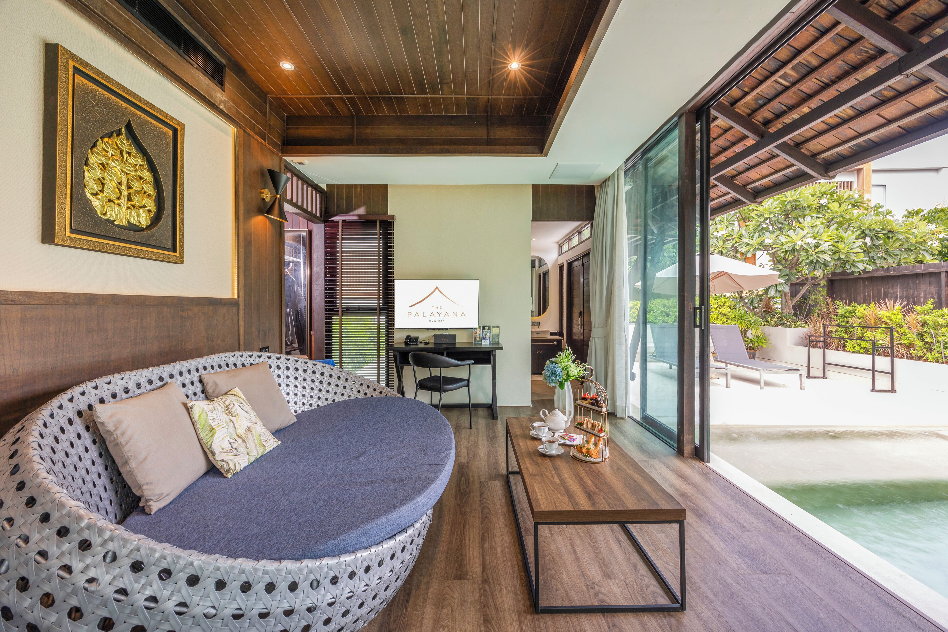 A modern room with a circular seating area, a desk, and a view of a pool.