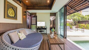A modern room with a circular seating area, a desk, and a view of a pool.