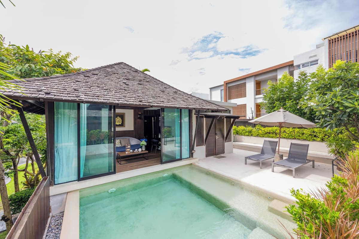 A modern house with a swimming pool, glass doors, and a patio with lounge chairs.