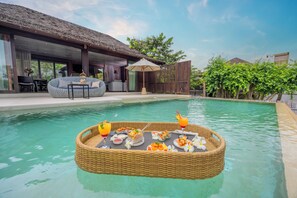 A poolside dining setup with a wicker table, lounge chairs, and a covered seating area. - The Palayana Hua Hin (Cha-am)