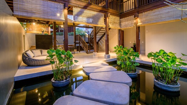 A modern interior with a wooden staircase, seating area, and potted plants. - The Palayana Hua Hin (Cha-am)