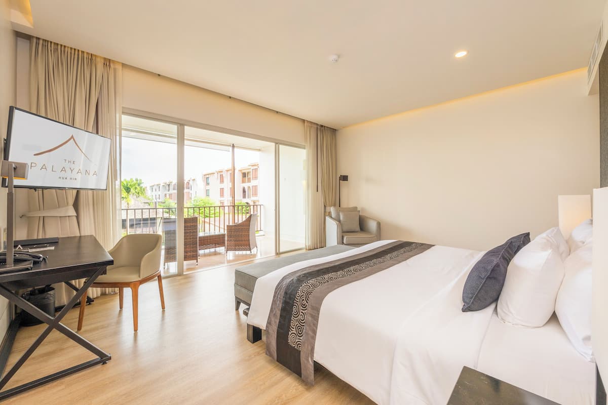 A hotel room with a bed, a desk, a chair, and a TV.