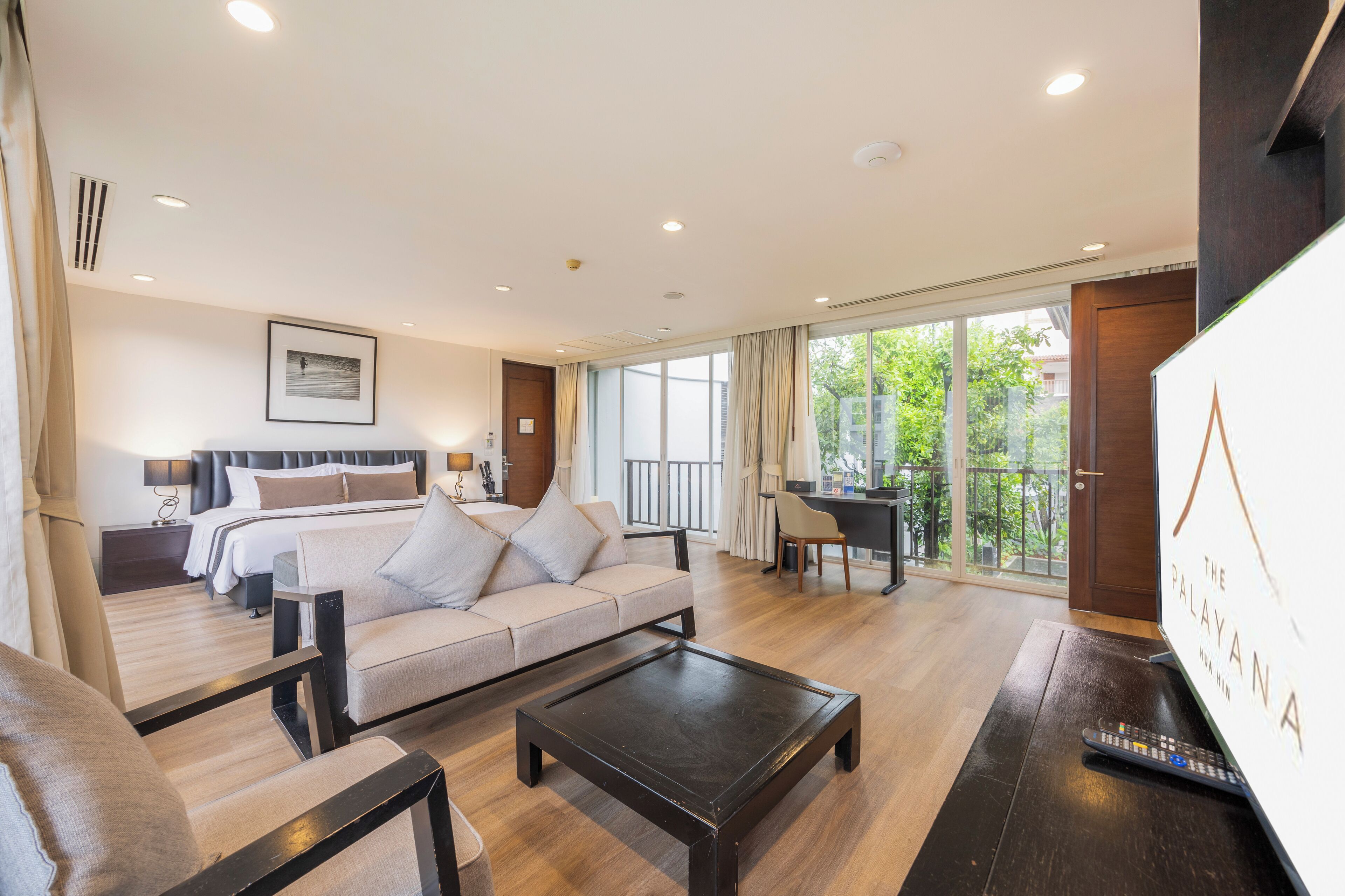 Une chambre d’hôtel moderne équipée d’un lit, d’un canapé, d’une table basse et d’un balcon avec vue.