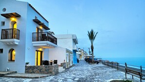 A coastal street with white buildings, stone steps, and a bench along the path. - Myrtos Mare Suites (Ierapetra)