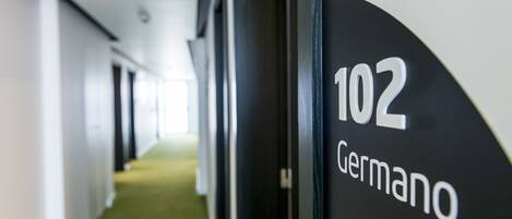 A hallway with a sign indicating room number 102 and the name 'Germano'.