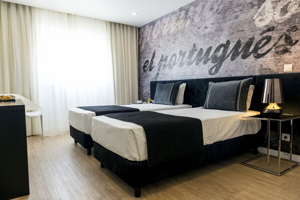 A hotel room with two beds, a desk, a chair, and a wall with the text "el portague". - Sport Hotel A Seleção (Setubal)
