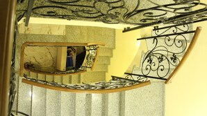 A spiral staircase with a marble-topped handrail and a decorative metal railing. - Hotel Villa Victoria (Tbilisi)