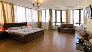 A hotel room with a large bed, a sofa, a TV, and a chandelier. - Hotel Villa Victoria (Tbilisi)