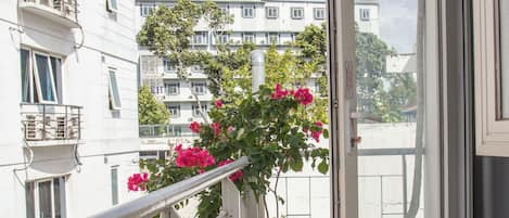 A balcony with potted plants and a view of adjacent buildings.