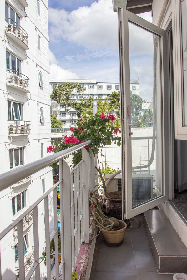 Un balcone con vasi di piante e vista sugli edifici vicini.