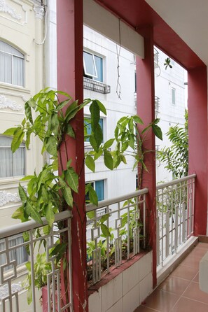Een balkon met rode pilaren, witte relingen en groene planten.