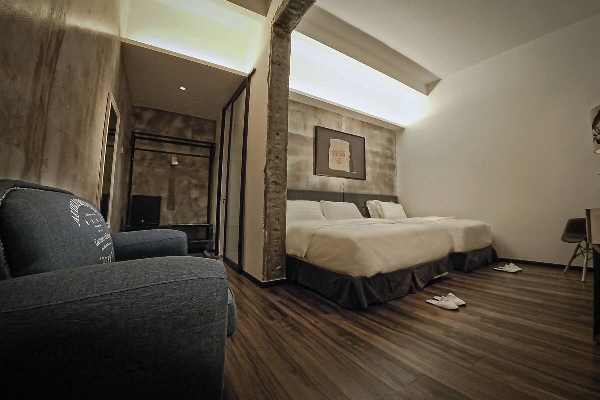 A hotel room with a bed, a chair, a desk with a lamp, and a framed picture on the wall.