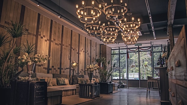 A spacious lobby with a high ceiling, multiple chandeliers, a wooden wall, and a large window offering a view of greenery. - Merton Hotel Ipoh (Ipoh)