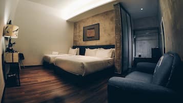A hotel room with two beds, a desk with a lamp, a chair, and a large window.
