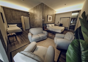 Une chambre d’hôtel comprenant un lit, deux canapés, une chaise, un bureau et un miroir.
