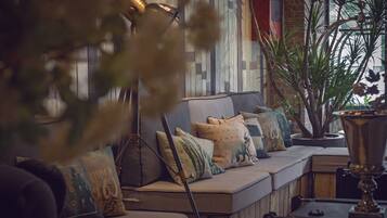 A cozy seating area with a sofa adorned with various cushions, a potted plant, and a brass lamp.