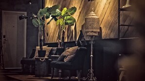 A room with a wooden wall, a potted plant, a chair, a small table, and a decorative lantern. - Merton Hotel Ipoh (Ipoh)