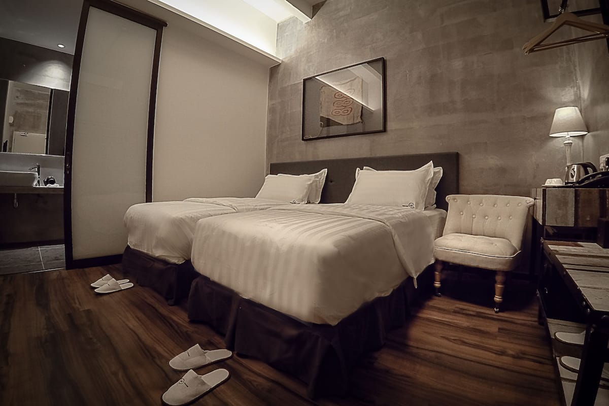 A hotel room with a double bed, a chair, a desk, and a mirror.