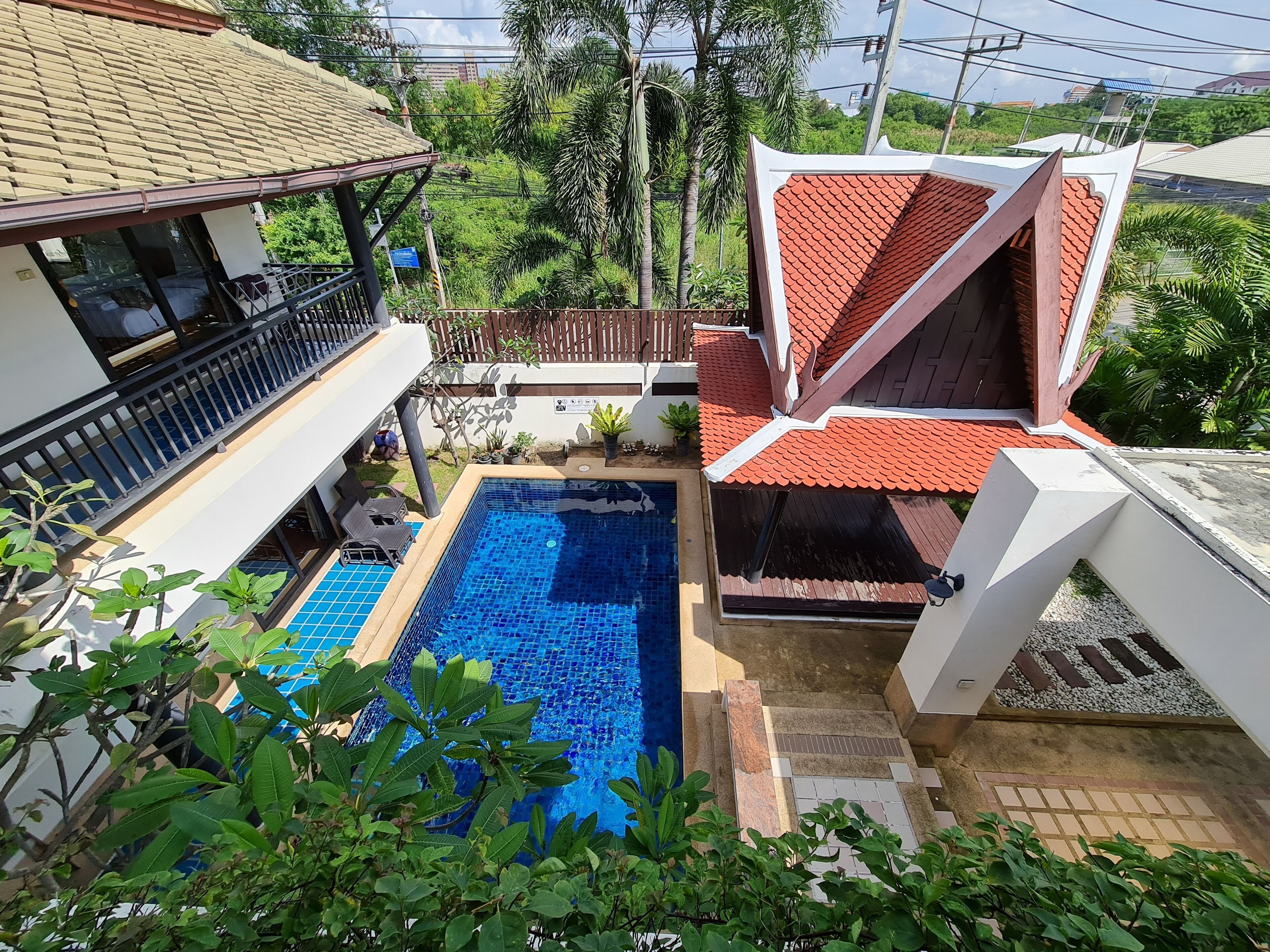 Una propiedad residencial con piscina, terraza cubierta y vistas a un paisaje verde exuberante.