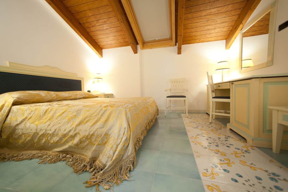 Un dormitorio con cama, una silla, un escritorio y un armario.