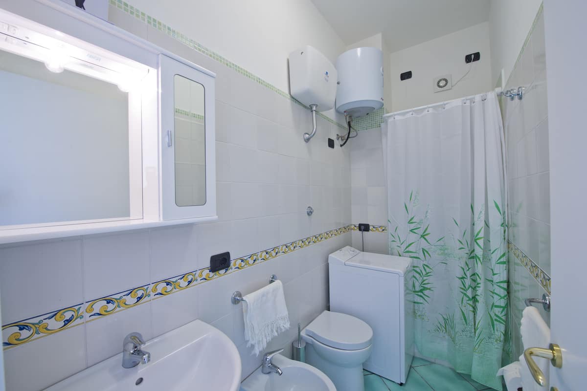 Baño con lavamanos, inodoro y cortina de ducha.