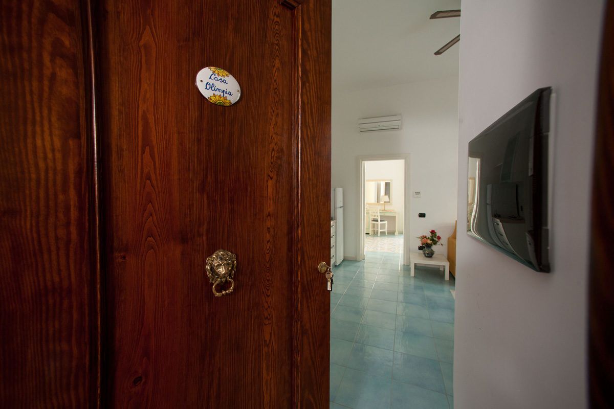 Une porte en bois avec une poignée en laiton et une enseigne indiquant « Casa Olimpia ».