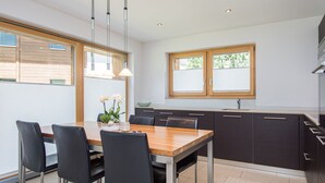 Eine moderne Küche mit einem Holztisch, schwarzen Stühlen und einem Fenster mit Jalousien.