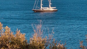 Un velero sobre aguas tranquilas, con una isla rocosa al fondo.