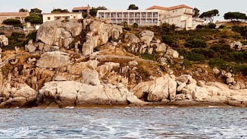 Ett hotell vid kusten med en bergig sluttning och utsikt över havet.
