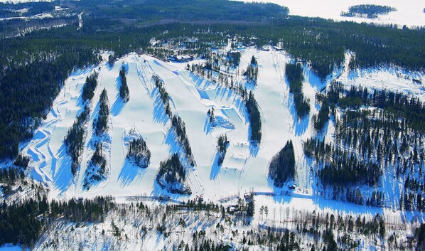 Paisaje montañoso cubierto de nieve con pistas de esquí y cabañas.