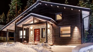 A log cabin with a stone entrance, a wooden door, and a covered porch. - Villa Borealis (Pälkäne)