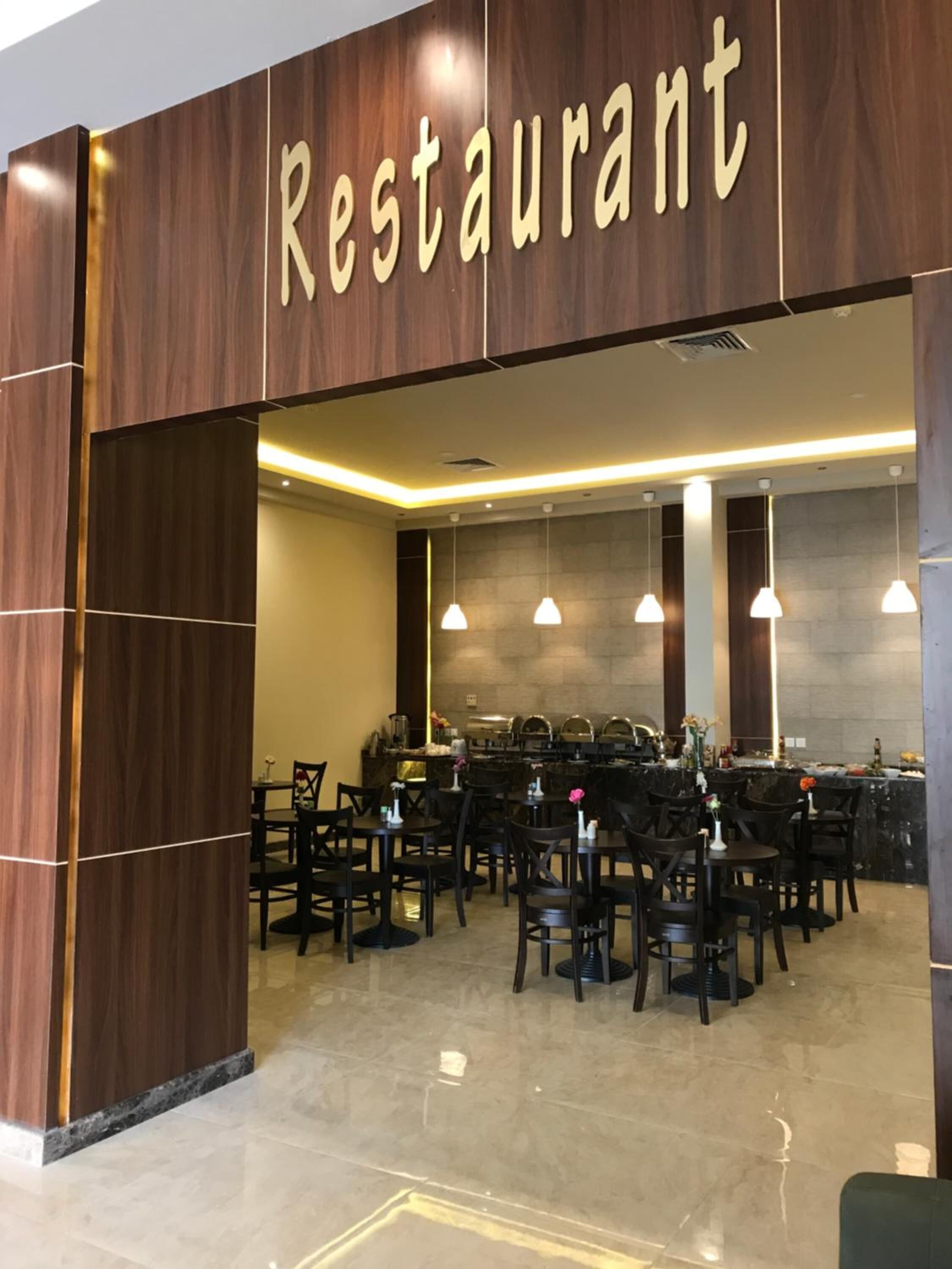 A restaurant with a modern interior, featuring a long counter and multiple tables with chairs.