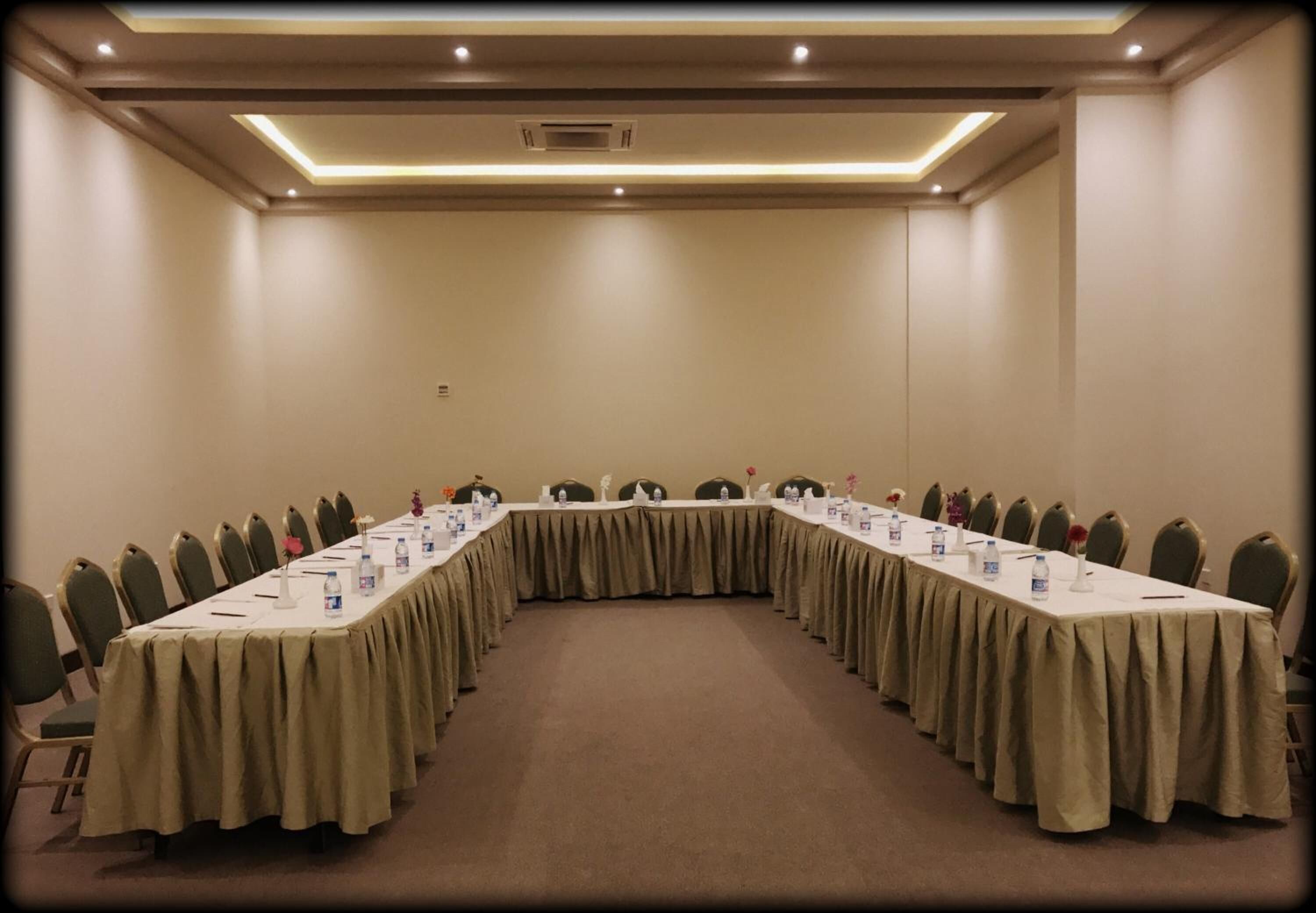 Un salón de conferencias con una larga mesa, sillas y piso alfombrado.