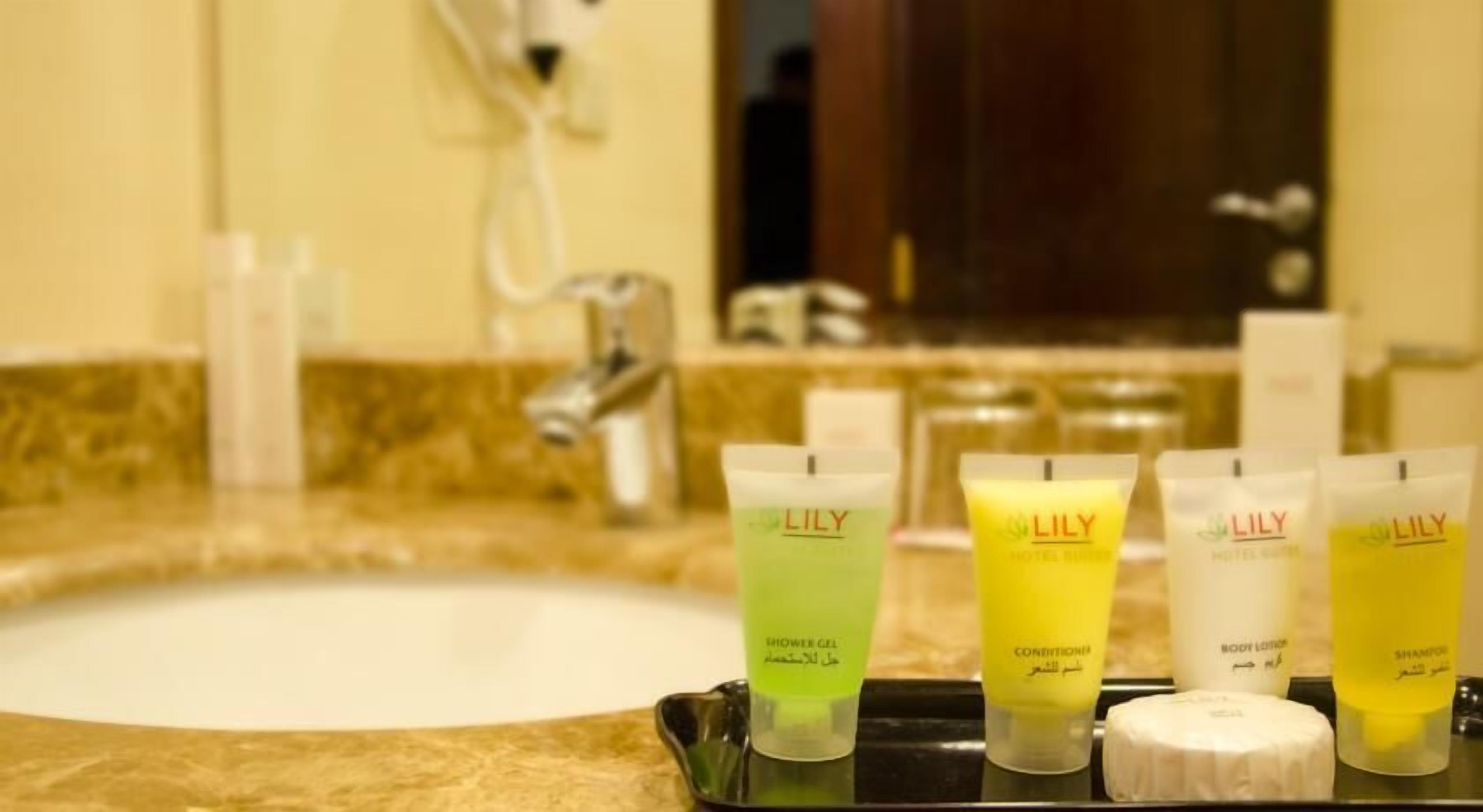 Un lavabo de salle de bain avec des articles de toilette, notamment du gel douche, de l’après-shampoing, une lotion pour le corps et du shampoing.