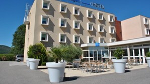 Een hotel met een moderne gevel, meerdere balkons en buiten zitgedeeltes.