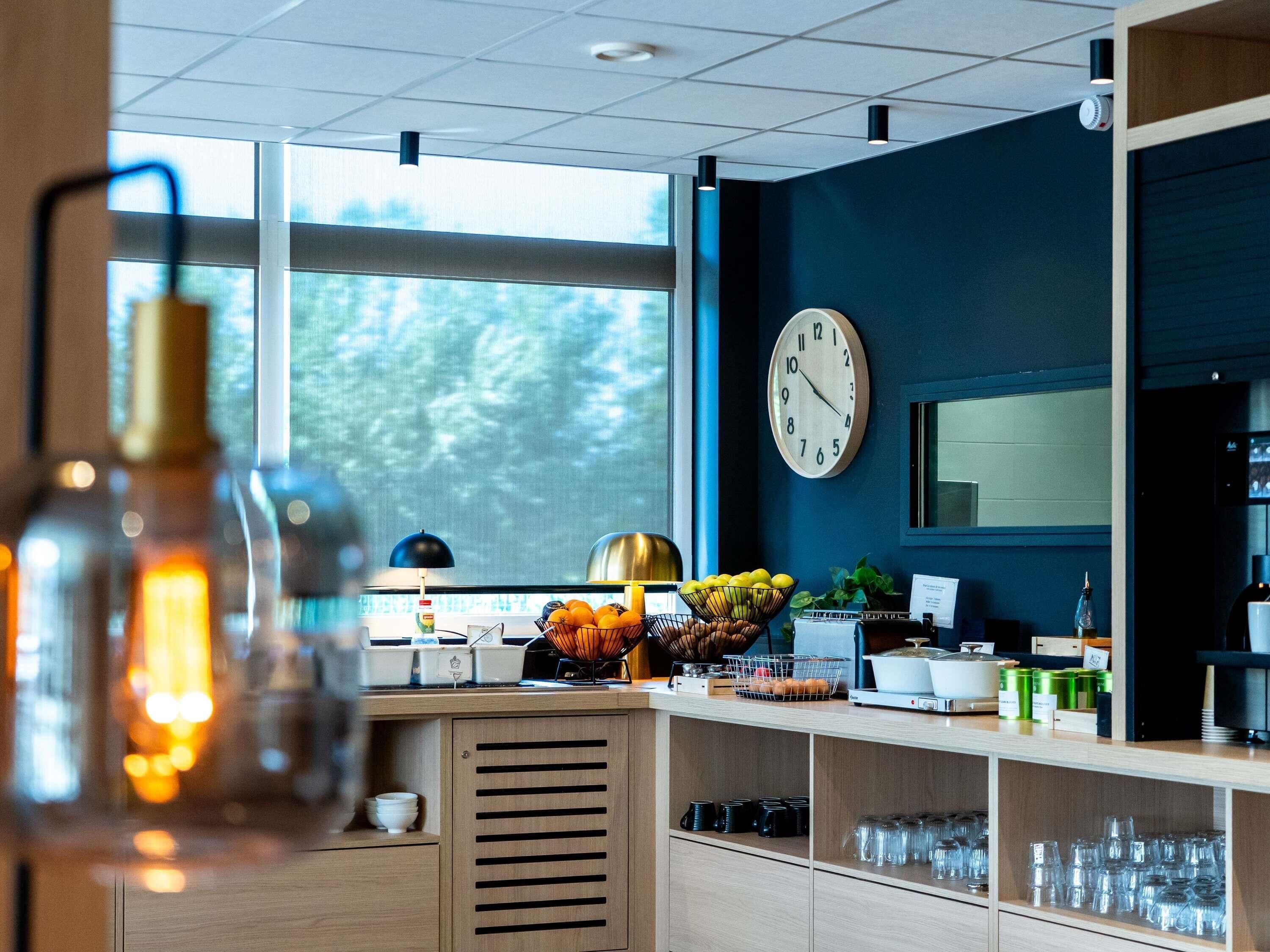 A modern kitchen with a large window, a clock, and various kitchen appliances.