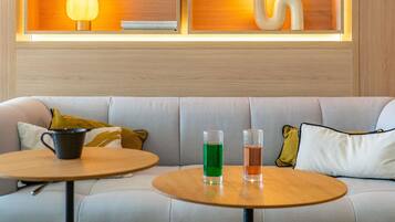 A modern interior with a sofa, two round tables, and a wall-mounted shelf with decorative items.