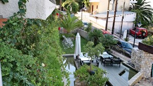 Un jardin sur le toit avec une piscine, du mobilier d’extérieur et un mur en pierre.
