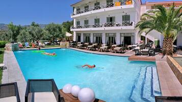 A pool area with lounge chairs and a building with balconies.