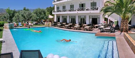 Una piscina al aire libre de temporada, sombrillas, tumbonas