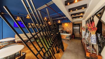 Un intérieur moderne comprenant un bar, des espaces pour s’asseoir et un comptoir d’accueil.