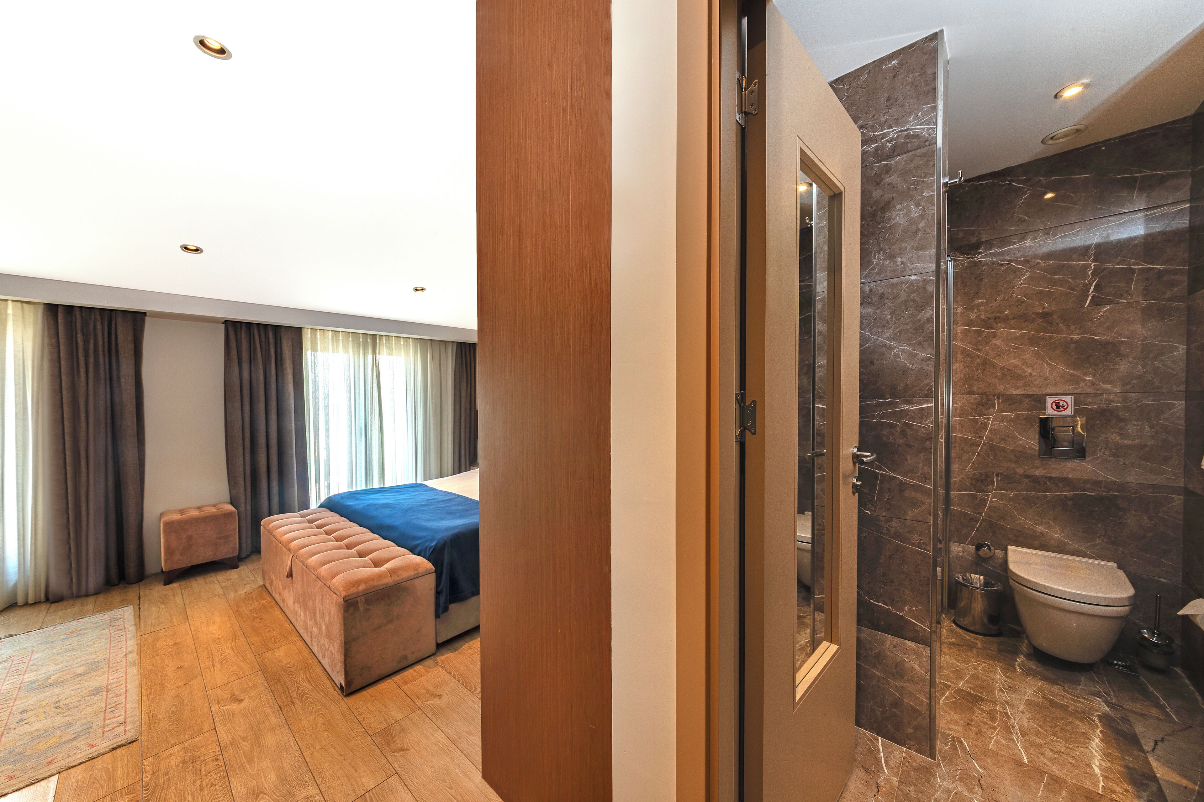 A hotel room with a bed, a seating area, and a bathroom with a shower and toilet.