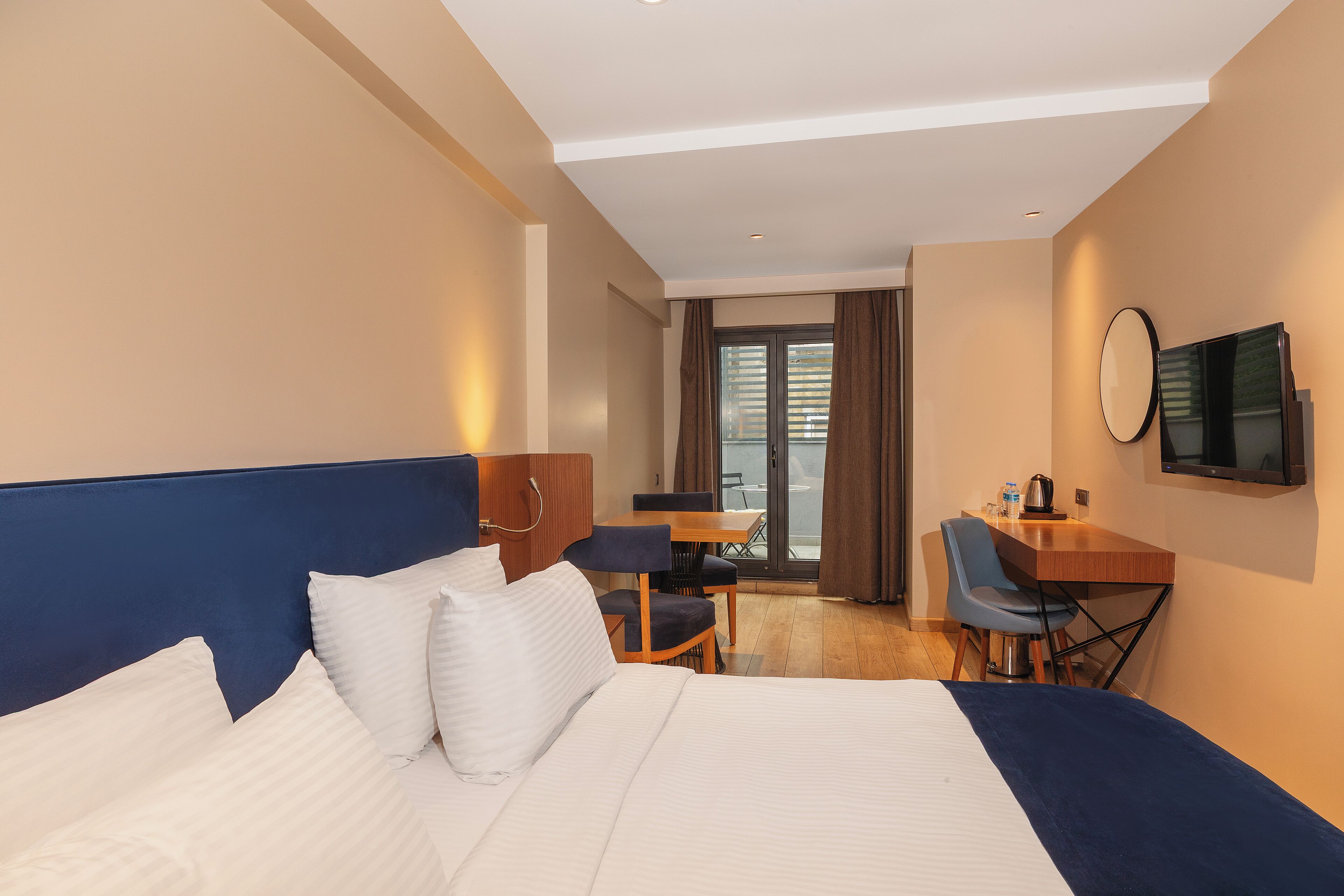 A hotel room with a bed, a desk, a chair, and a television.