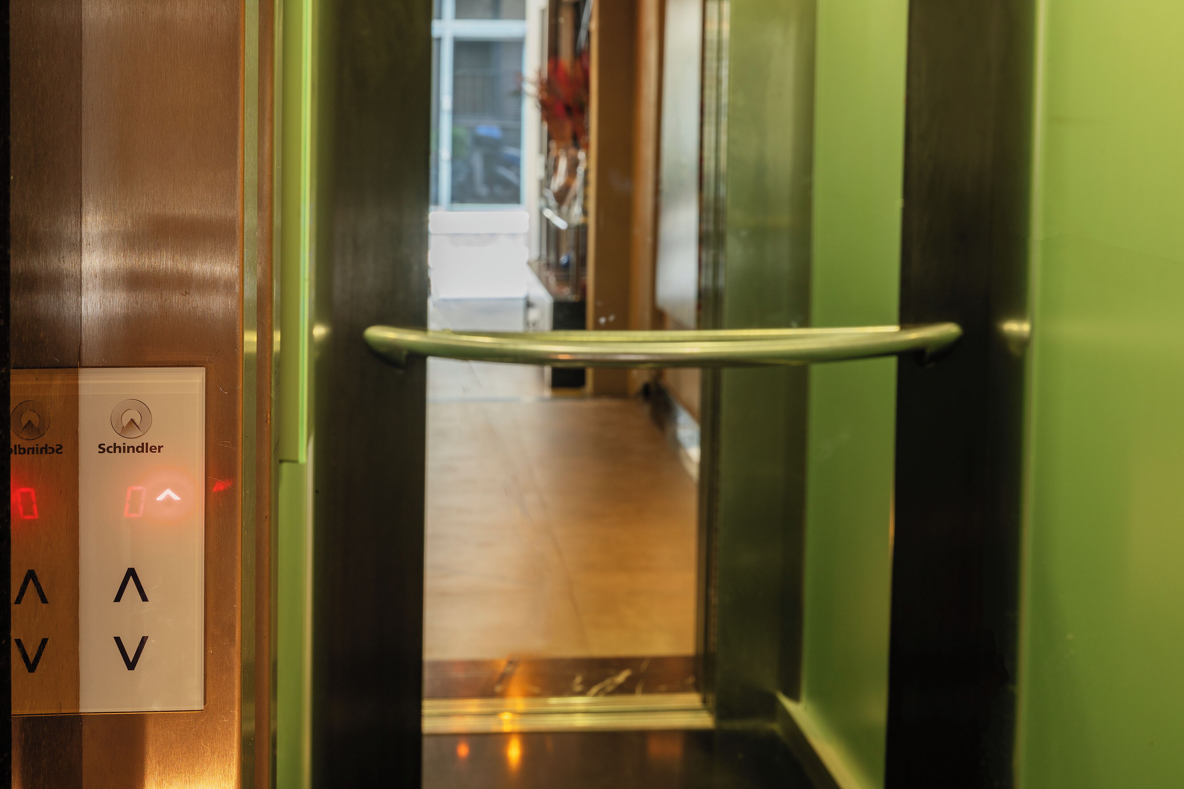An elevator interior with a metallic handrail and control panel with directional arrows.