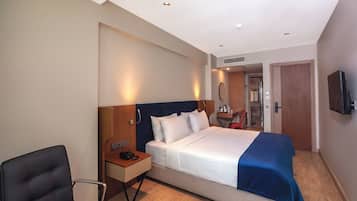 Une chambre d’hôtel avec un lit, une table de chevet, une chaise et un téléviseur fixé au mur.