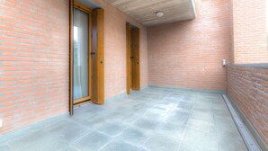 A corridor with brick walls and a tiled floor, leading to a door with a glass panel. - Domus (Ravenna)