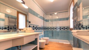 A modern bathroom with a wooden floor, a sink with a towel rack, a toilet, and a shower area. - Domus (Ravenna)