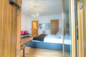 Un dormitorio con cama, candelabro, puerta de madera y un cuadro en la pared.