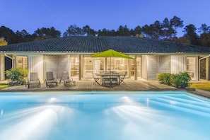 A swimming pool with a wooden deck, outdoor furniture, and a covered patio area with a green umbrella. - Lagrange Vacances La Clairière aux Chevreuils (Moliets-et-Maa)