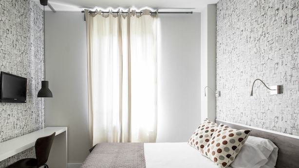 Une chambre à coucher moderne avec un lit, un bureau et un téléviseur.